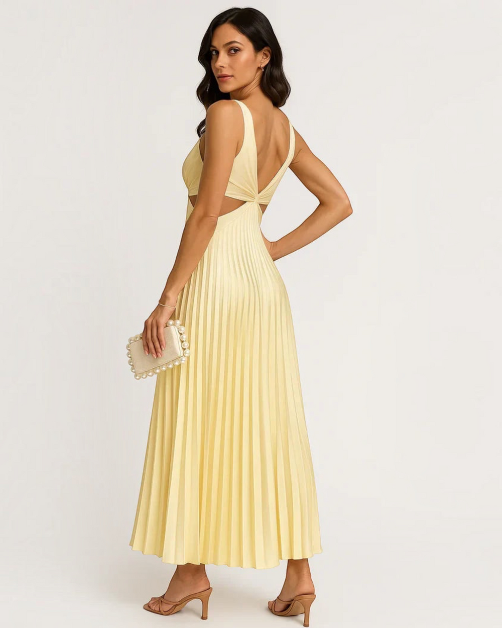 Luna Moda yellow pleated maxi dress with a V-neck, cut-out waist, and flowing skirt, styled with a pearl clutch.