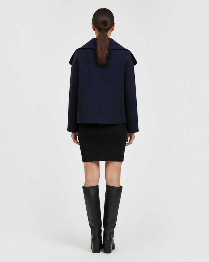 Back view of a model wearing a Luna Moda navy blue double-breasted mid-season coat with a wide collar.