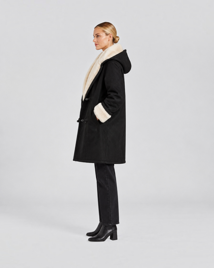 Luna Moda black hooded winter coat with cream faux fur lining and toggle buttons worn by a woman in profile