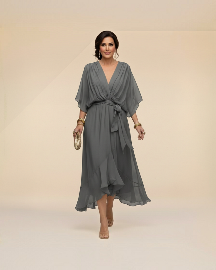 Luna Moda Monica grey chiffon midi dress with V-neck and tie waist worn by a woman in a studio setting.