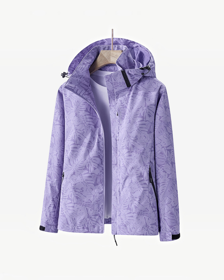 Luna Moda lightweight purple waterproof rain jacket with a tropical leaf print and adjustable hood on a hanger