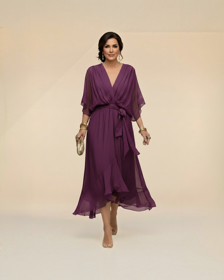 Luna Moda Monica purple chiffon midi dress with V-neck, draped waist tie, and flowing skirt worn by a woman.