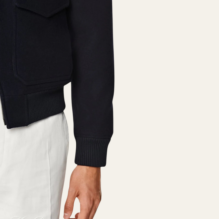 Luna Moda black vegan wool bomber jacket with ribbed cuffs and flap pockets, worn over white trousers.
