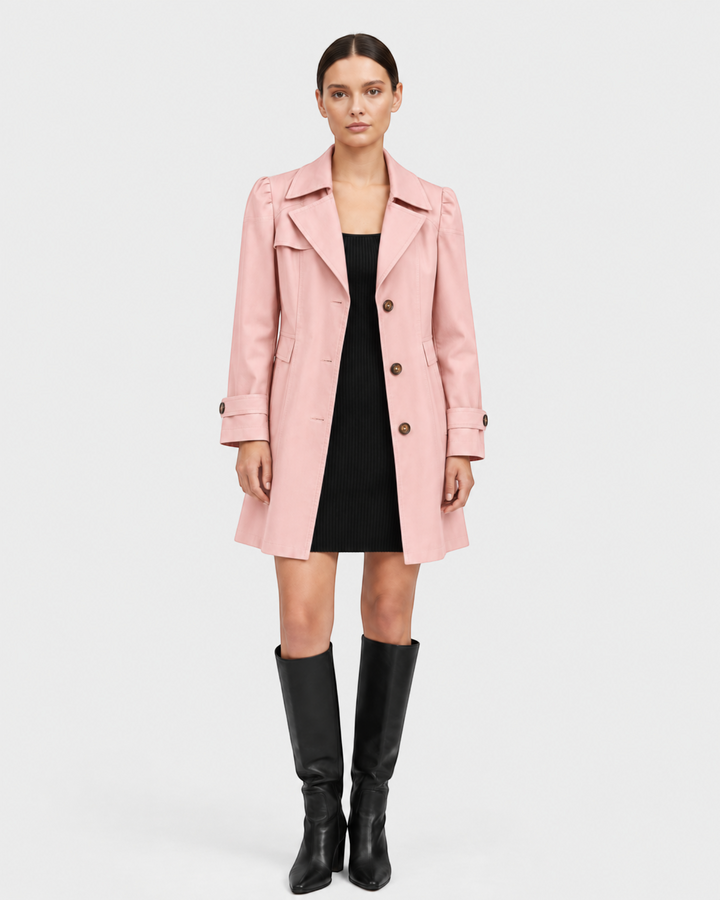 Luna Moda light pink flared trench coat in gabardine fabric worn by a model over a black dress and knee-high boots.