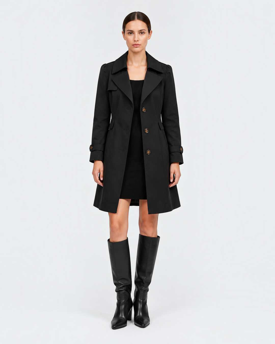 Luna Moda black flared trench coat in lightweight gabardine worn by a model with a black dress and knee-high boots.