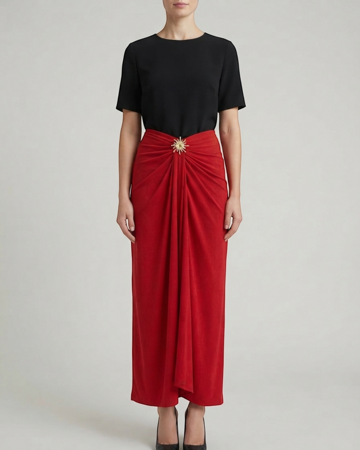 Luna Moda red midi skirt with elegant draping and a gold sun-shaped brooch worn with a black top