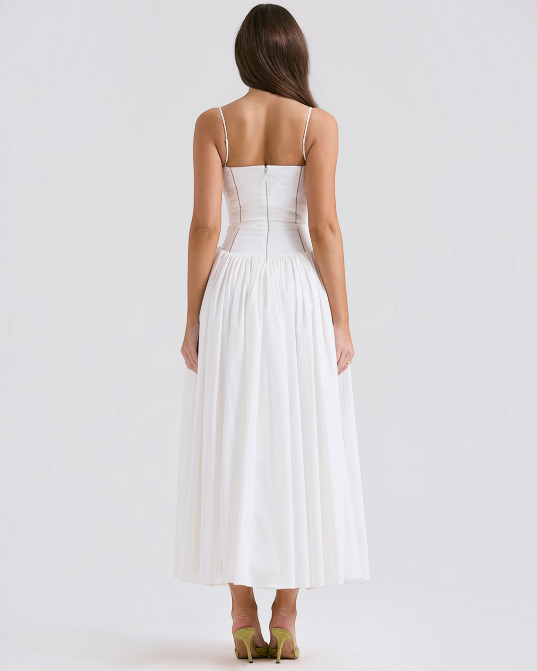 Back view of a model wearing a Luna Moda white midi dress with a fitted bodice and spaghetti straps.