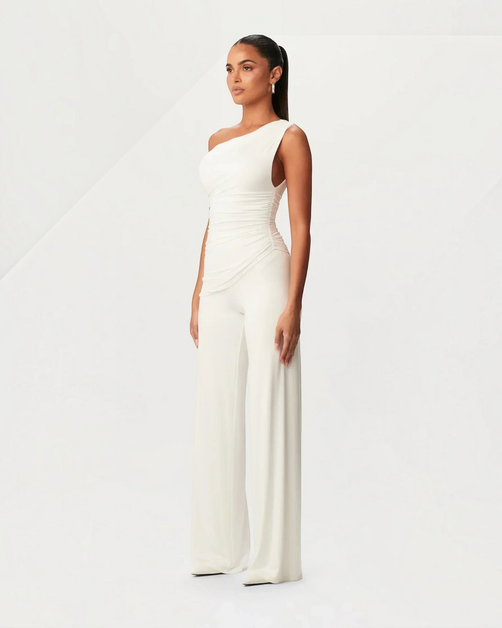 Luna Moda white asymmetrical one-shoulder jumpsuit with side ruching worn by a model in a studio setting