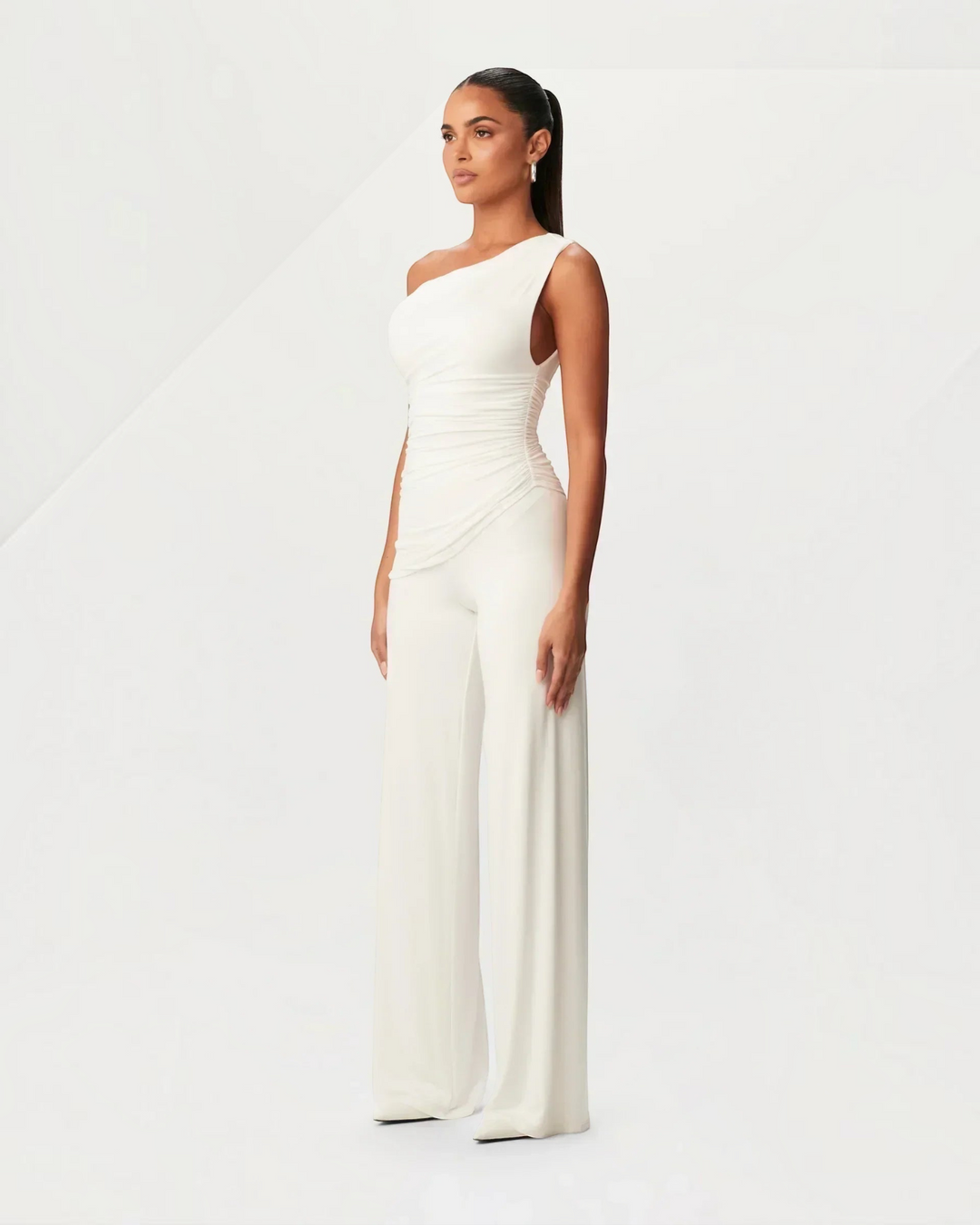 Luna Moda white asymmetrical one-shoulder jumpsuit with side ruching worn by a model in a studio setting