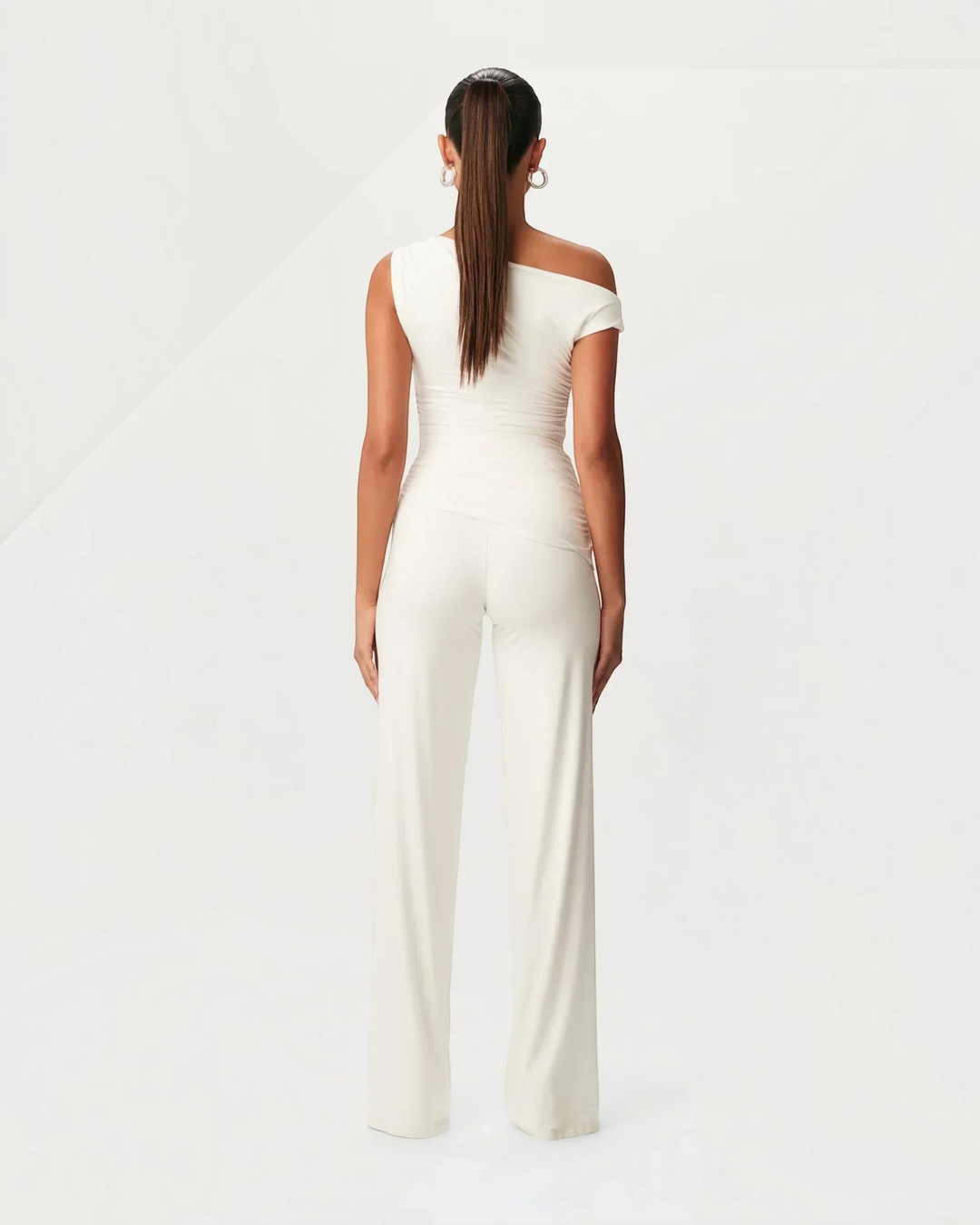 Luna Moda white asymmetric two-piece set with side ruching and wide-leg trousers worn by a model, back view.