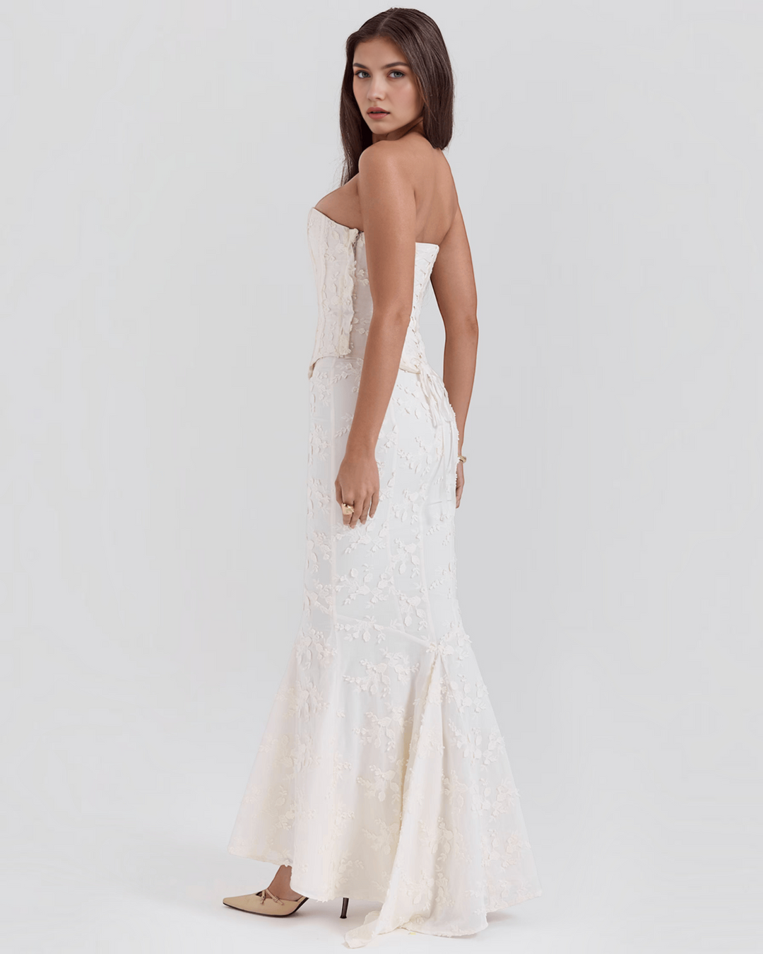 Luna Moda ivory floral embroidered corset dress with a flared hem worn by a model in a side profile view