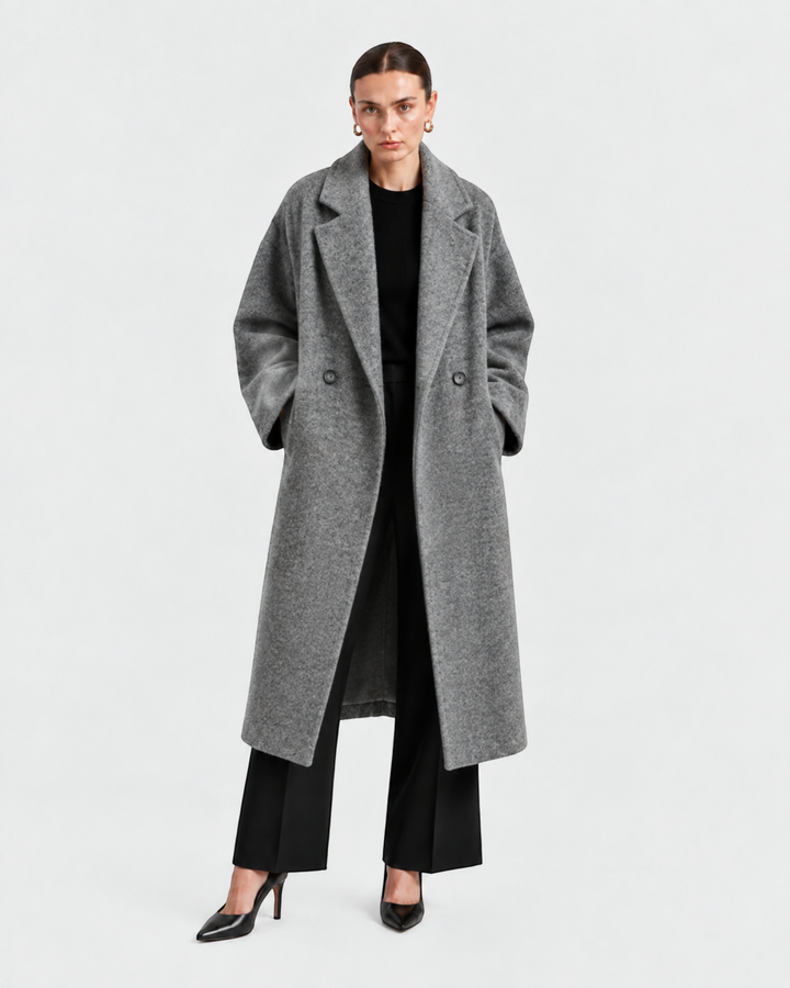 Model wearing a Luna Moda long grey wool coat with a wide collar and pockets over a black outfit against white background