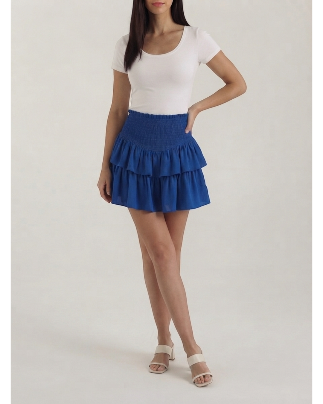 Luna Moda Grace mini skirt in royal blue with a high-waisted smocked waistband and layered ruffled hem on a model.