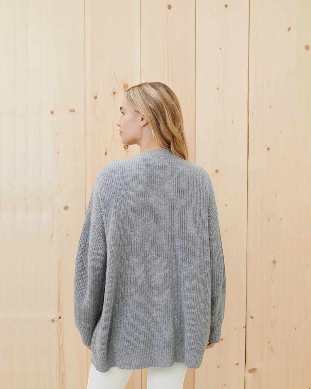 Luna Moda grey cashmere cardigan with ribbed texture worn by a woman, back view against a light wood background.