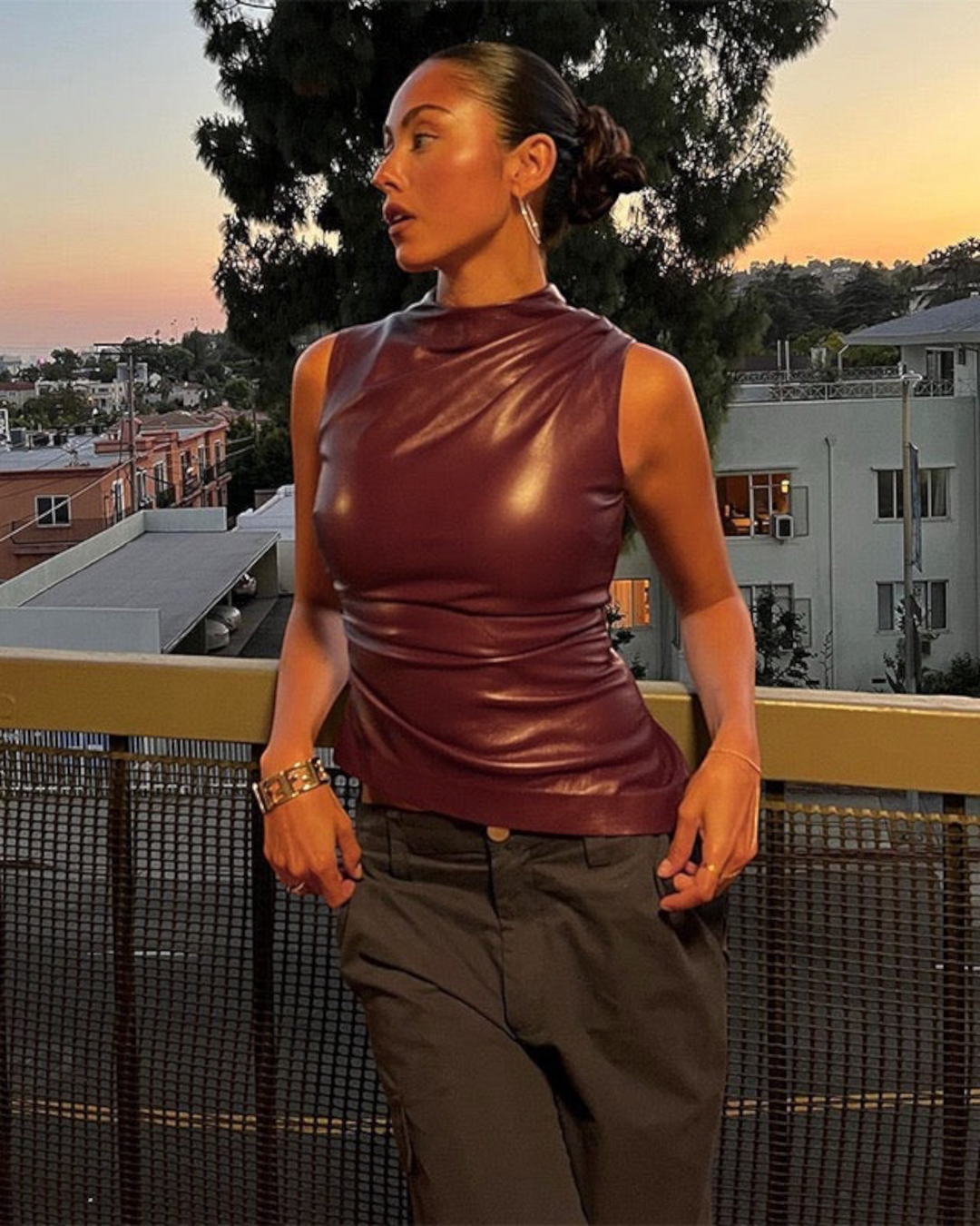 Luna Moda sleeveless burgundy faux leather top with a sculpted fit worn by a model on a balcony at sunset