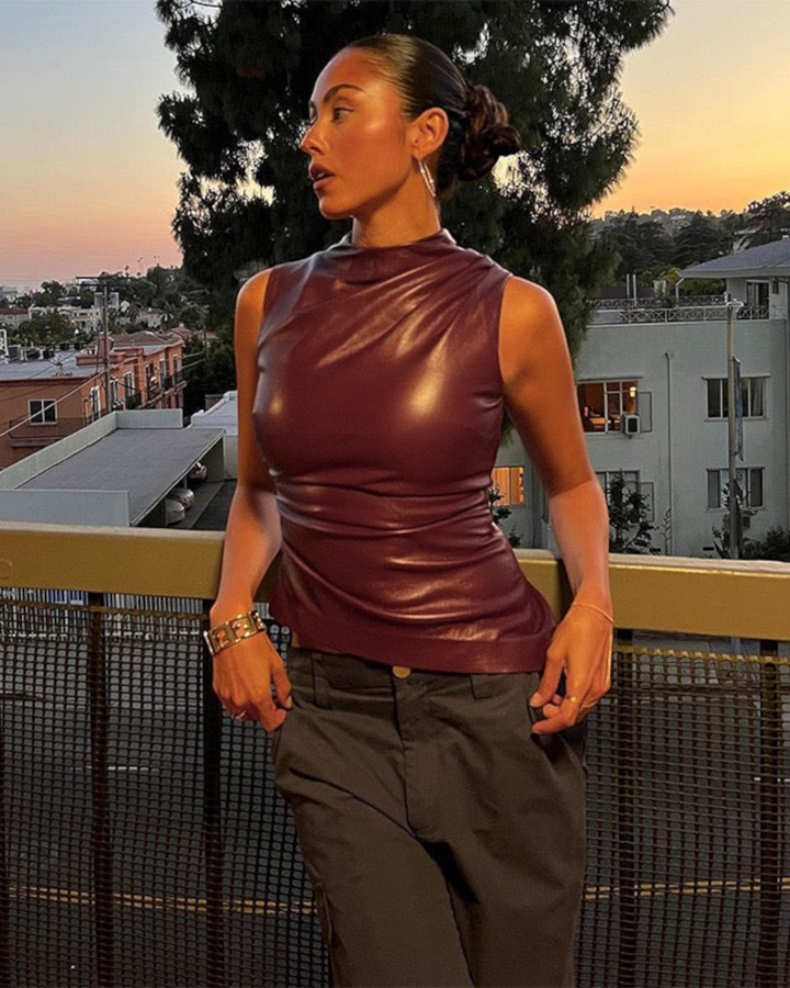 Luna Moda sleeveless burgundy faux leather top with a sculpted fit worn by a model on a balcony at sunset