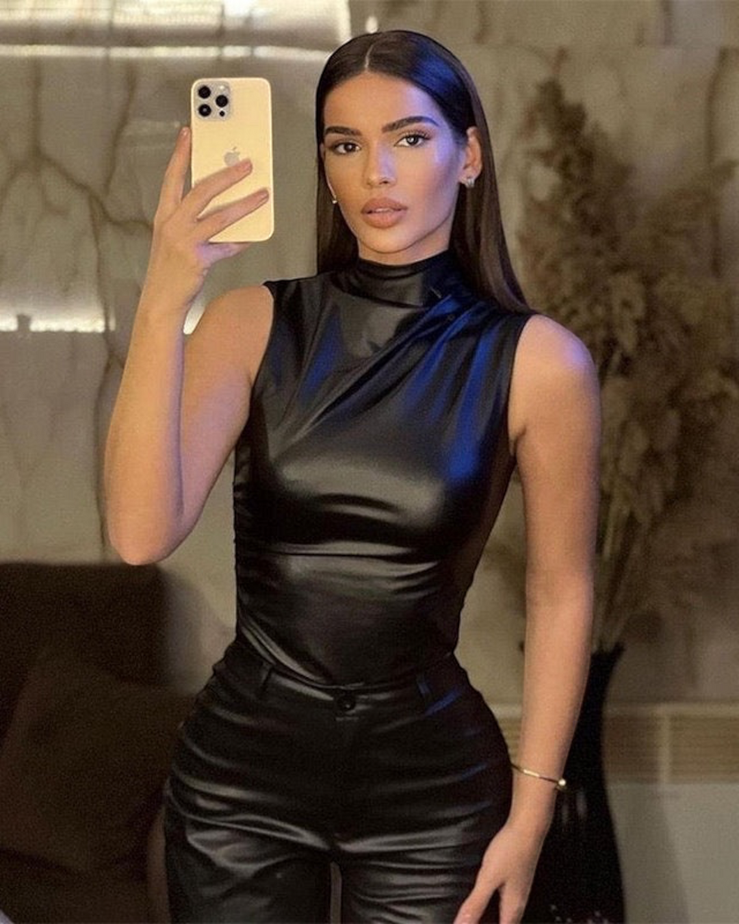 Luna Moda sleeveless black faux leather top with a high neck, worn by a woman taking a mirror selfie.