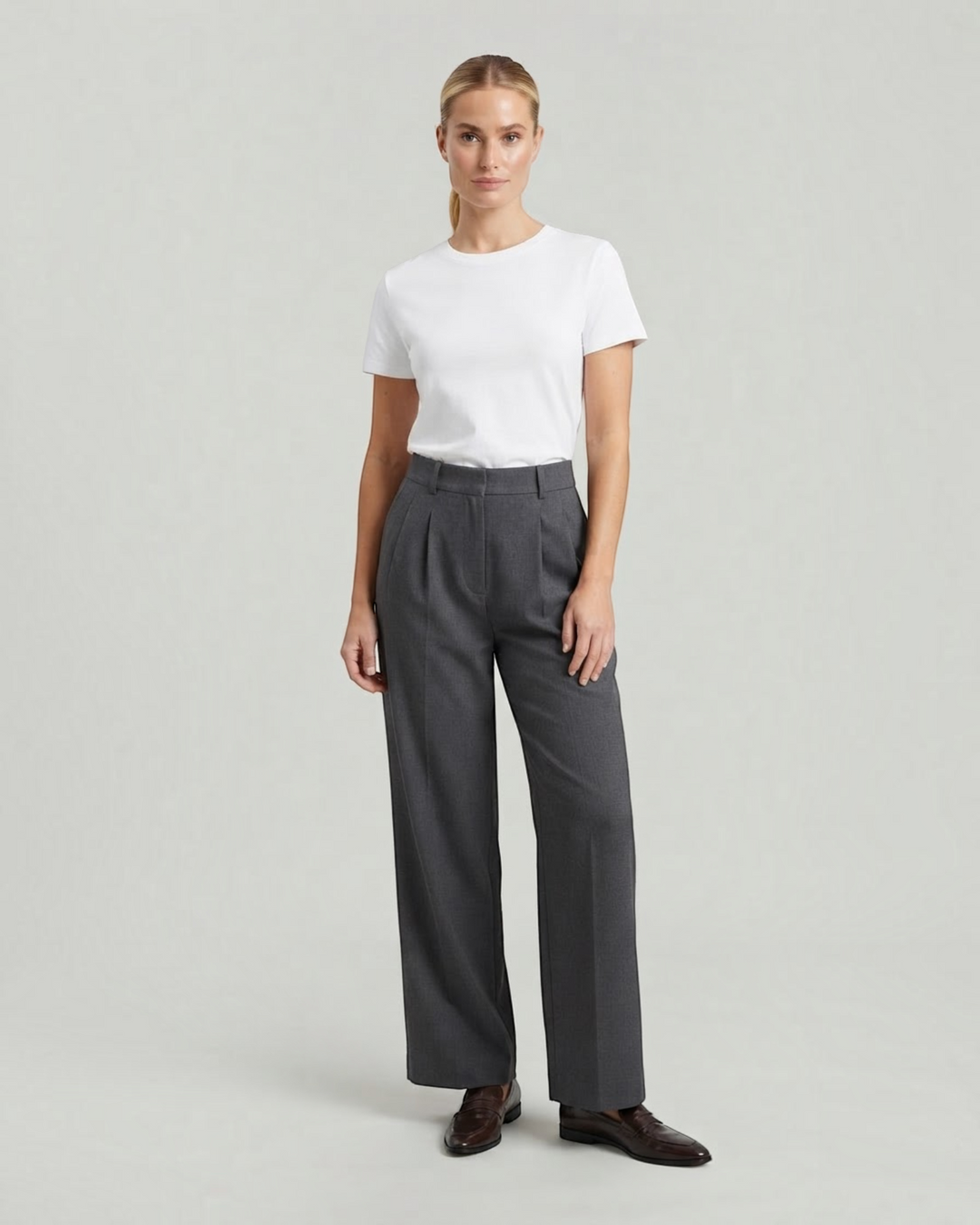 Model wearing Luna Moda high-waisted charcoal grey pleated palazzo trousers with a white t-shirt and loafers