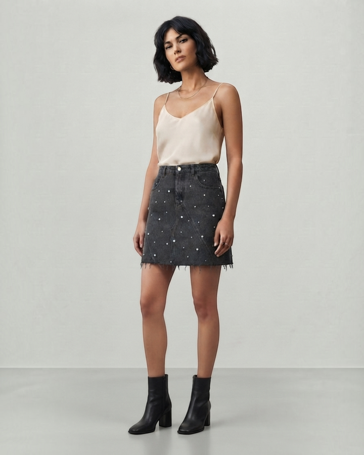 Luna Moda black denim mini skirt with pearl embellishments and raw hem worn by a model with a beige camisole