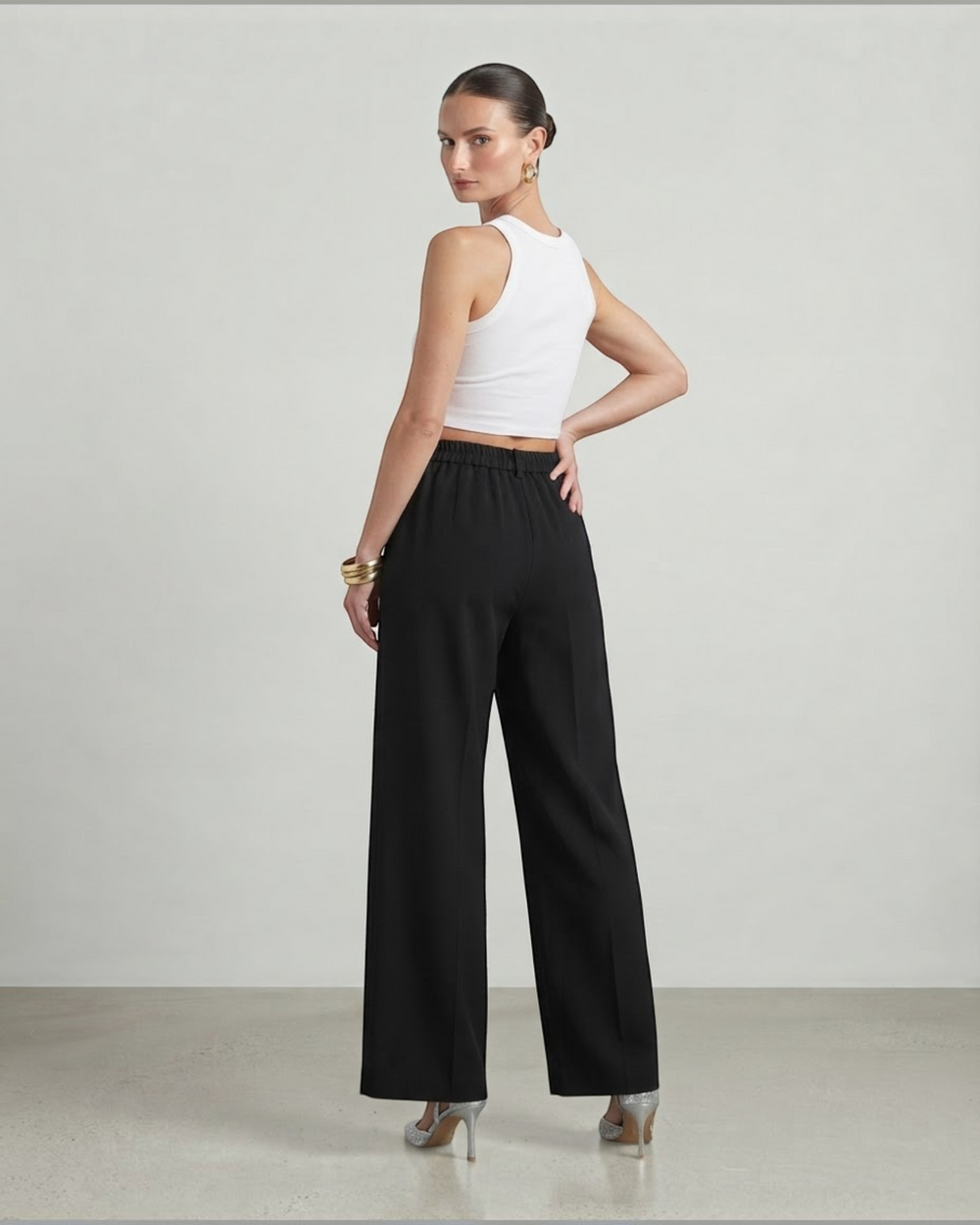 Luna Moda high-waisted black palazzo trousers with a fluid wide-leg cut worn by a model from the back view.