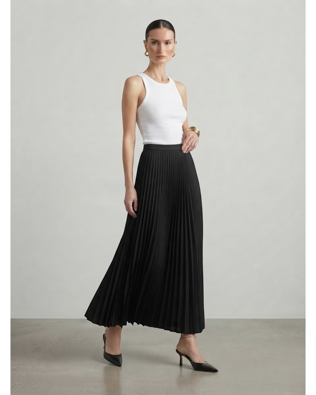 Luna Moda high-waisted black pleated maxi skirt worn by a model with a white tank top and black heels