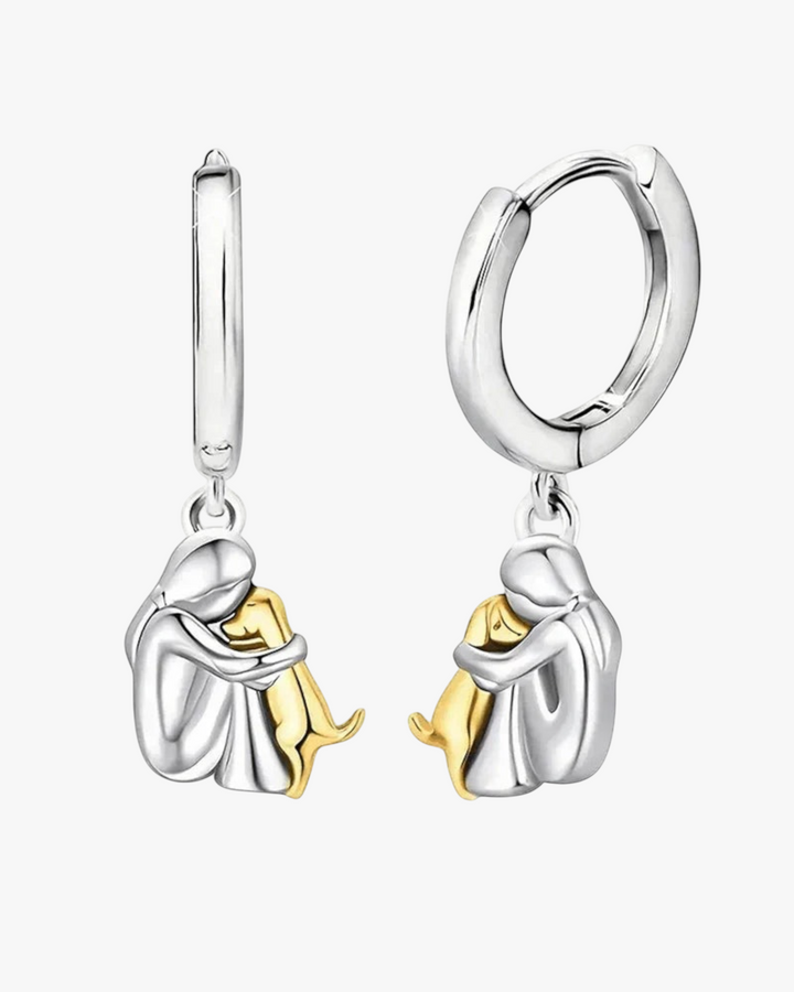 Luna Moda two-tone silver and gold hoop earrings featuring a person hugging a dog, symbolizing love and companionship.