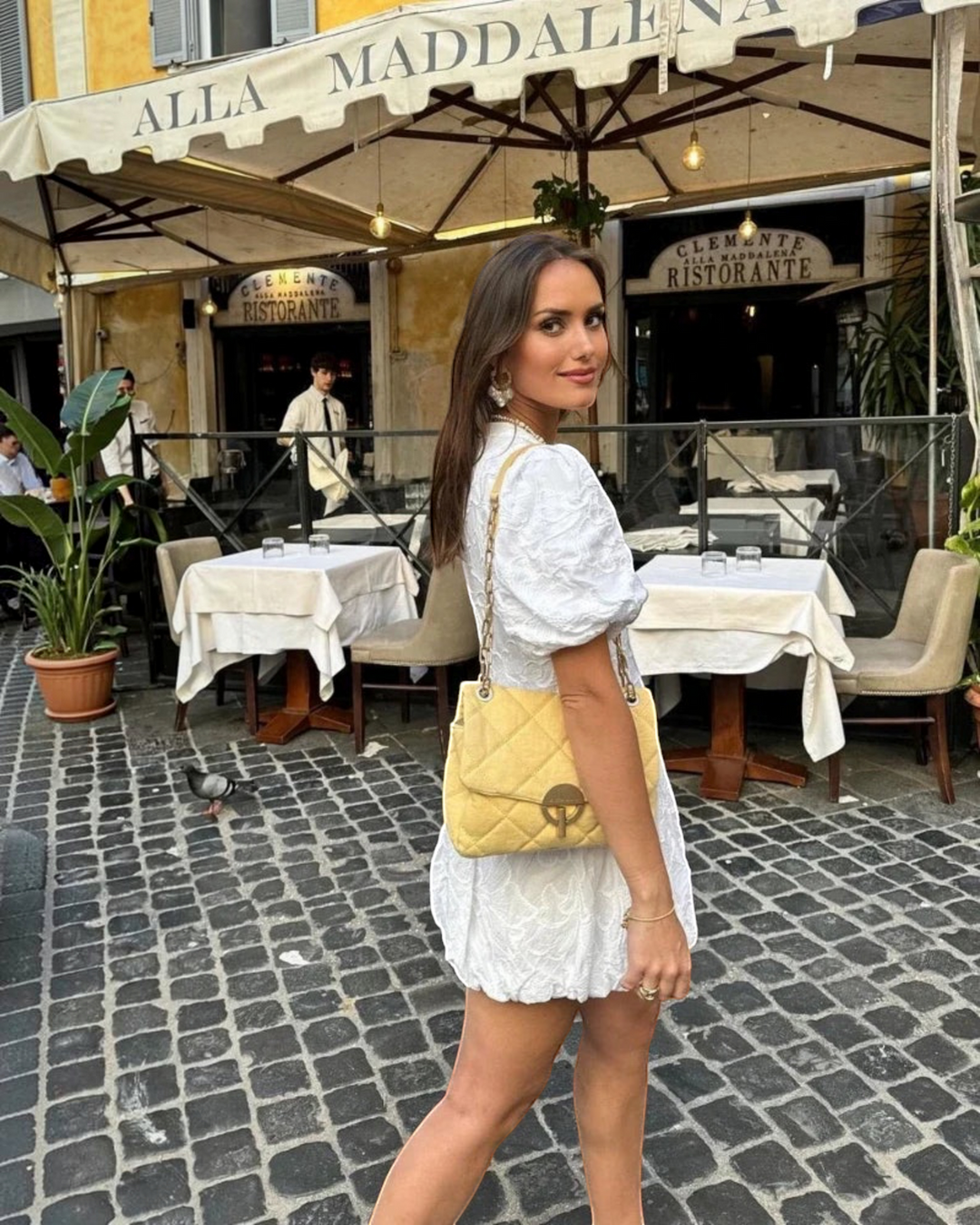 Luna Moda white mini dress with puff sleeves and delicate embroidery worn by a woman with a yellow quilted bag