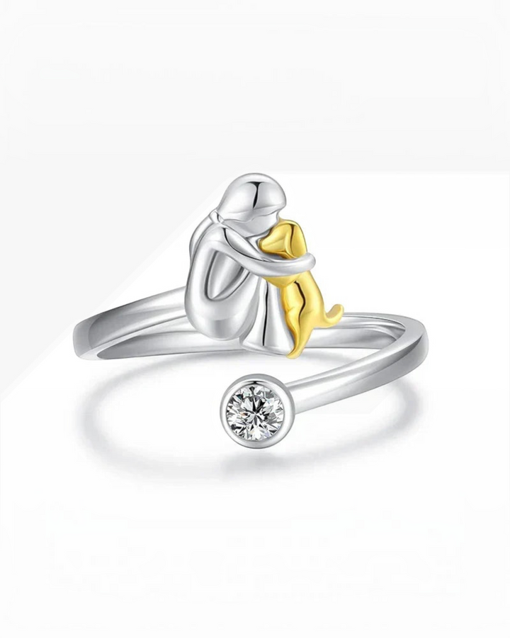 Luna Moda silver ring featuring a person hugging a gold dog with a sparkling crystal accent