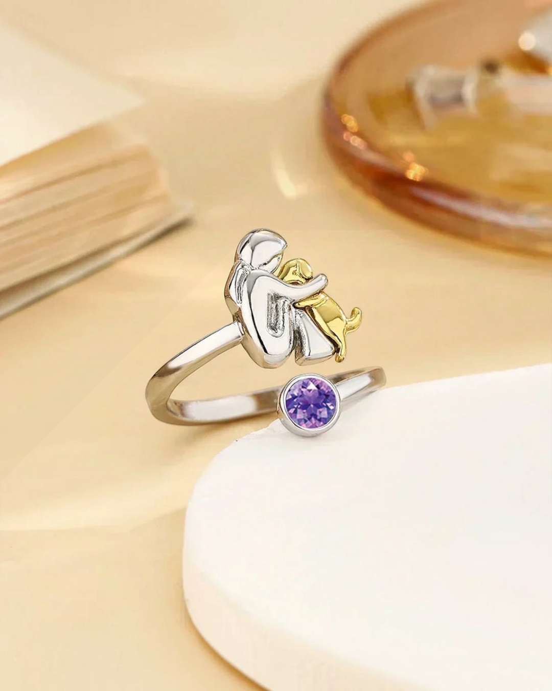 Luna Moda ring featuring a silver human and gold dog embrace design with a purple crystal accent