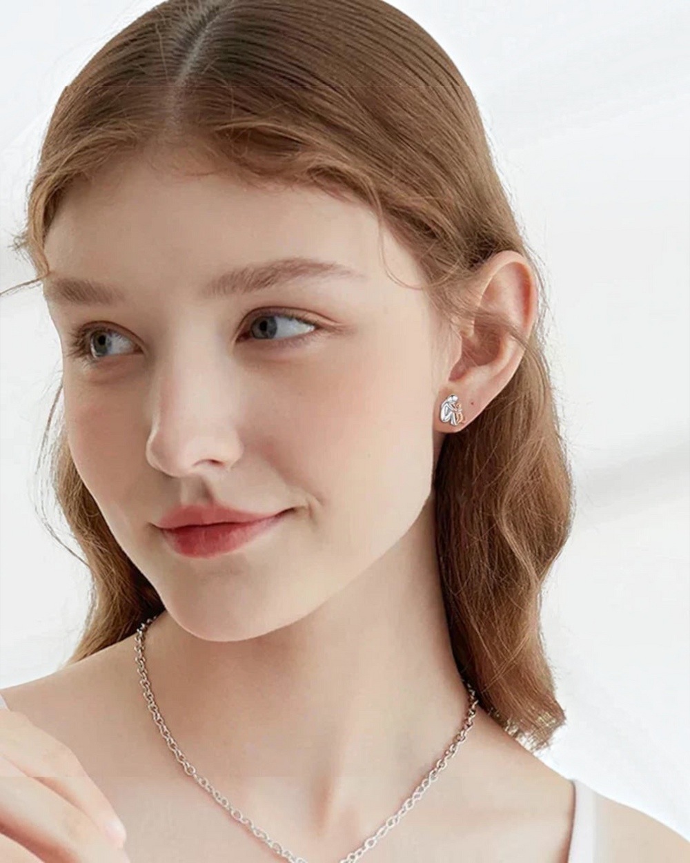 Luna Moda two-tone silver and pink cat-shaped stud earrings worn by a woman with light brown hair