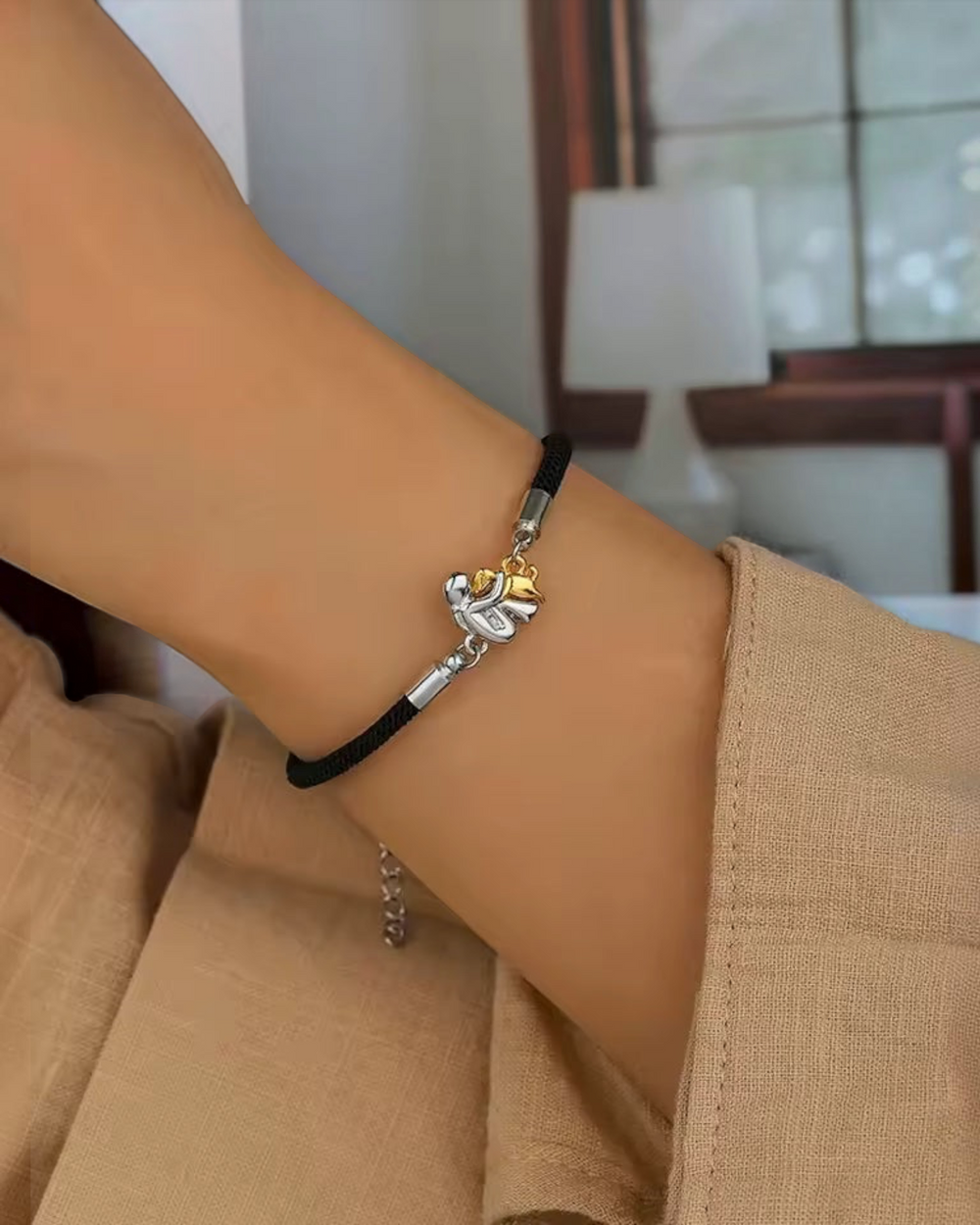 Luna Moda adjustable black cord bracelet featuring a two-tone silver and gold dog pendant on a woman's wrist