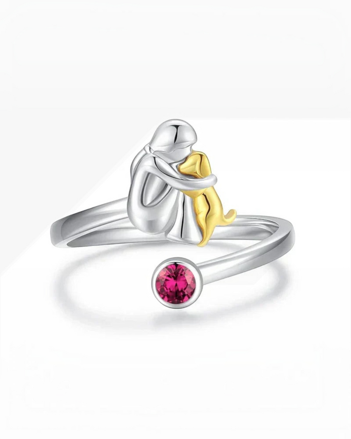 Luna Moda adjustable ring featuring a silver person hugging a gold dog with a pink crystal accent