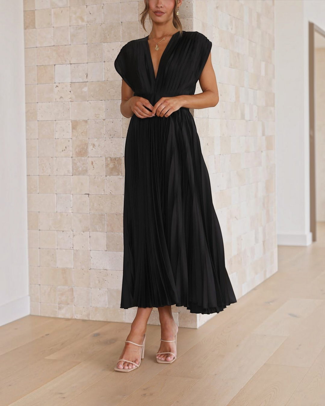 Luna Moda Isla black pleated midi dress with deep V-neck and high waist, worn by a model in a neutral setting.