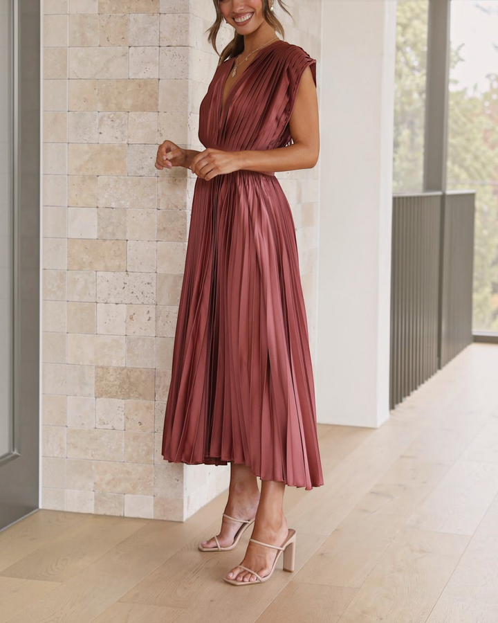 Luna Moda Isla pleated midi dress in rose red with a deep V-neck and high waist, worn with beige heeled sandals.