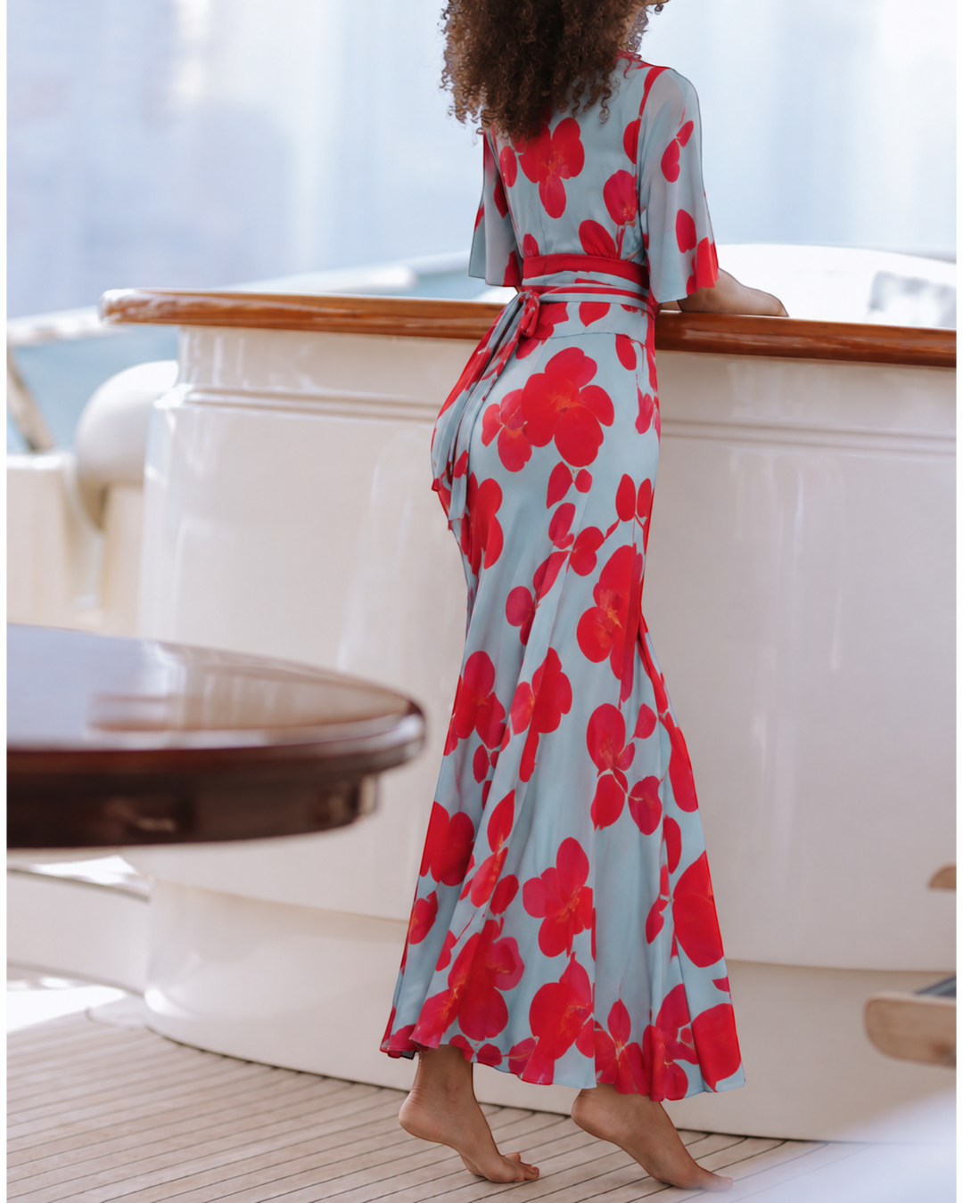 Luna Moda Valentina maxi dress in light blue with red floral print, featuring a tied waist and flowing silhouette.