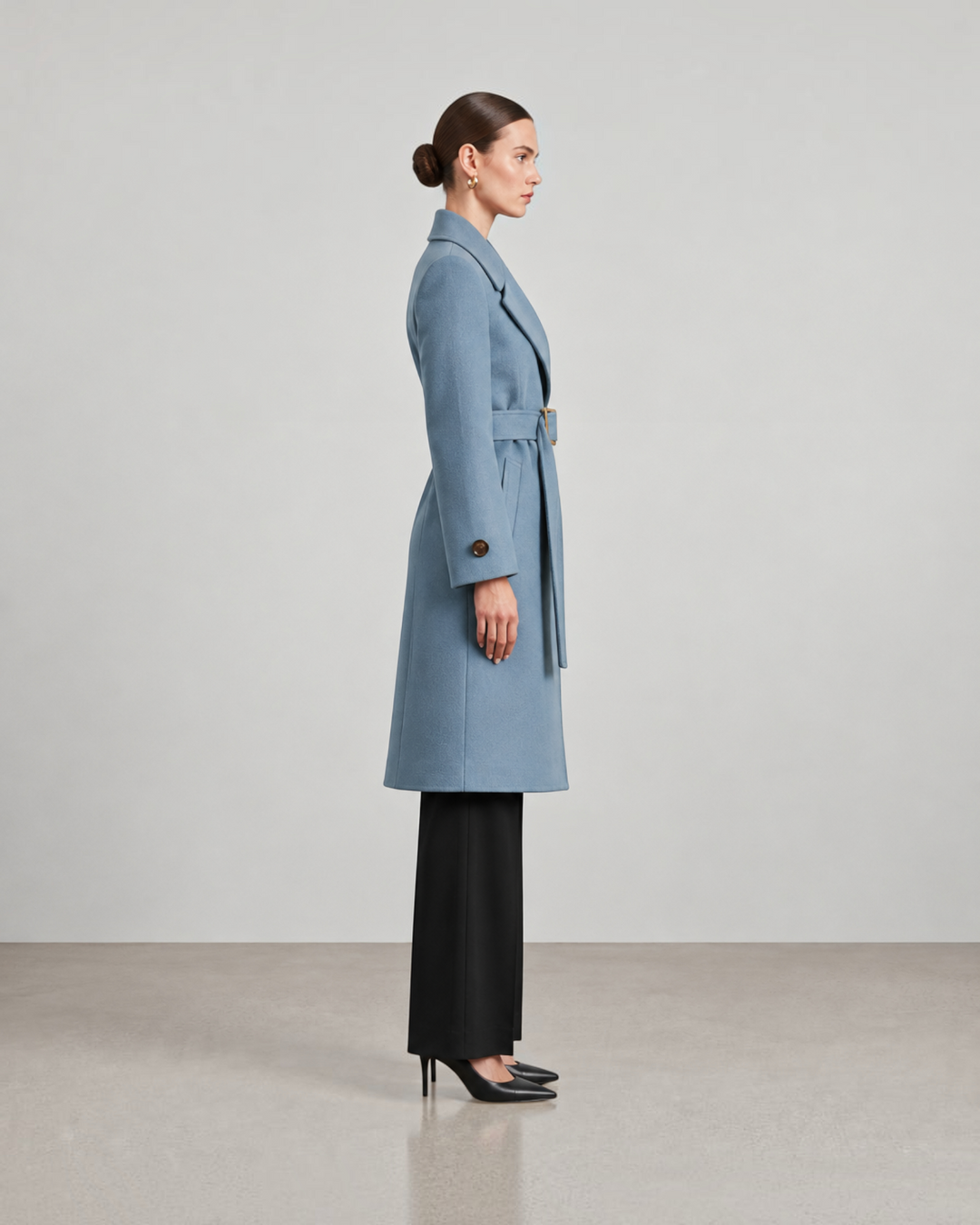 Luna Moda light blue long coat with a belted waist worn by a model in profile view against a neutral background