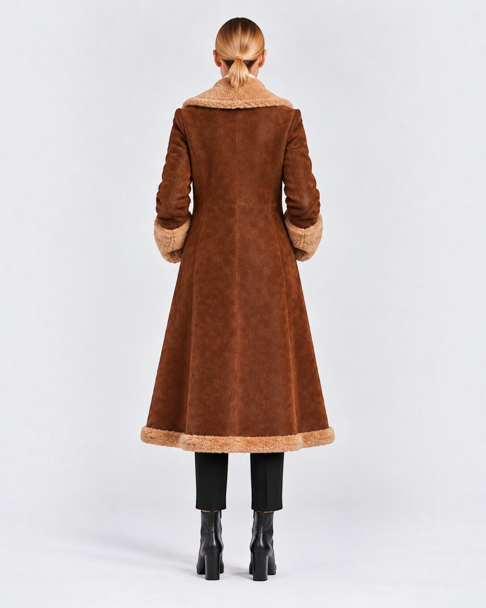 Back view of a woman wearing a long brown Luna Moda winter coat with beige faux fur trim on the collar, cuffs, and hem.