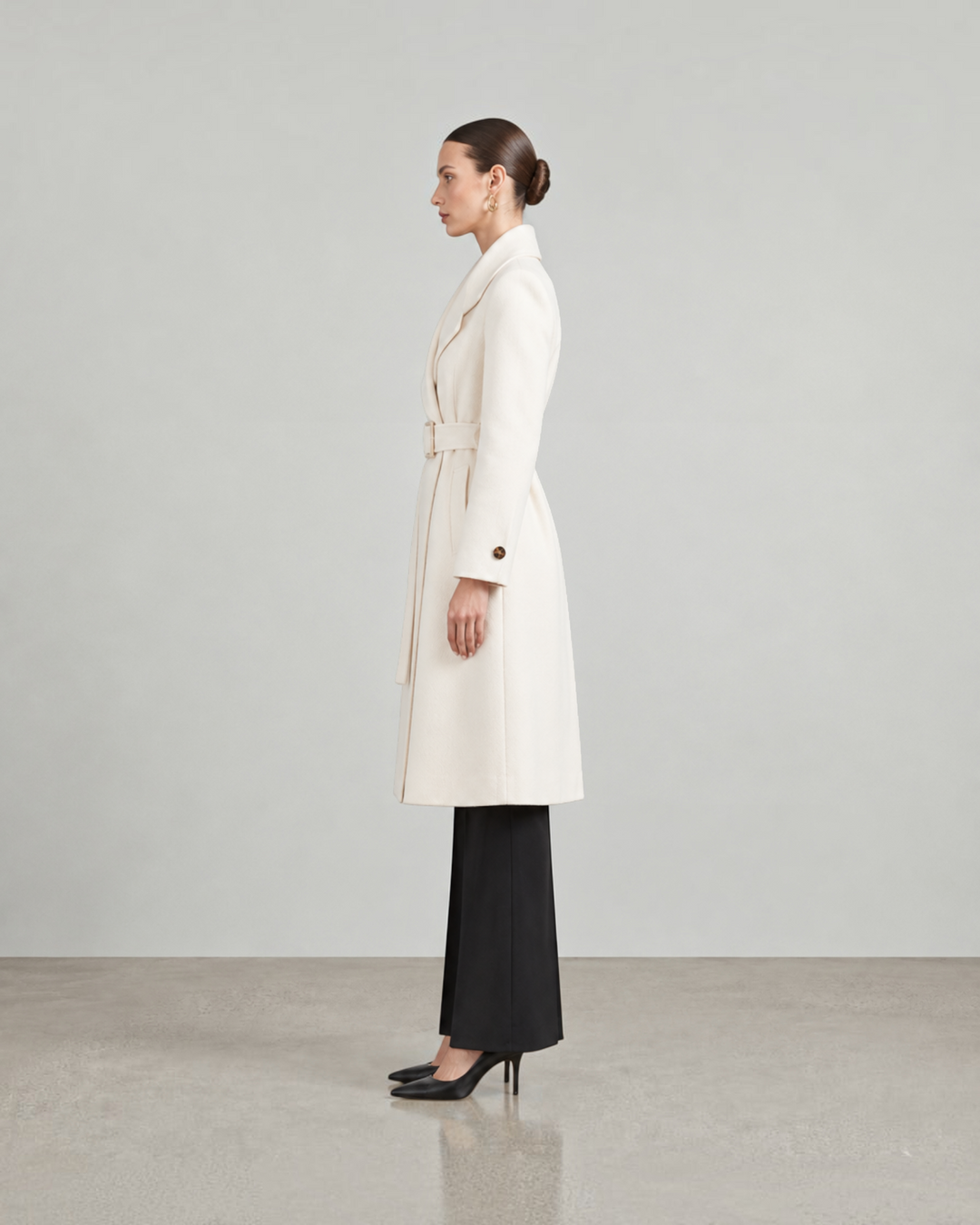 Luna Moda LISABETTA long cream wool coat with a belted waist worn by a model in a side profile view
