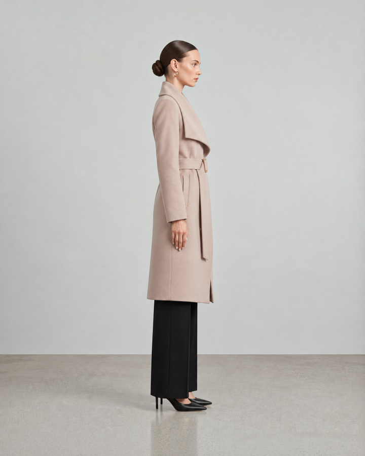 Luna Moda beige long belted coat worn by a model in profile view, featuring a shawl collar and tailored silhouette.