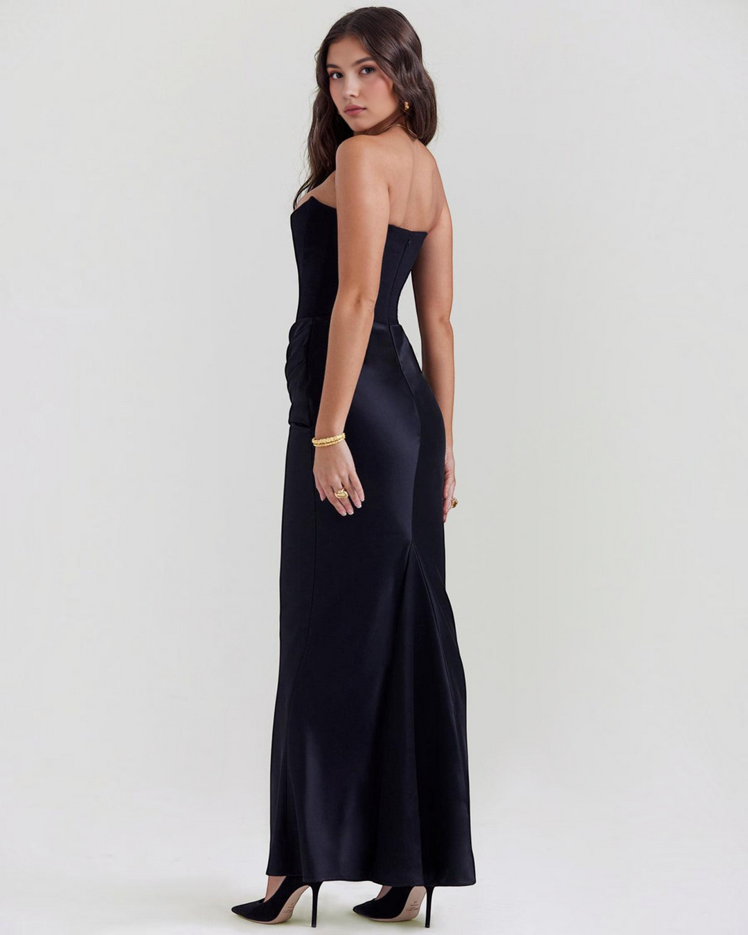 Luna Moda Serene strapless black satin evening gown with draped waist detail worn by a model in profile view