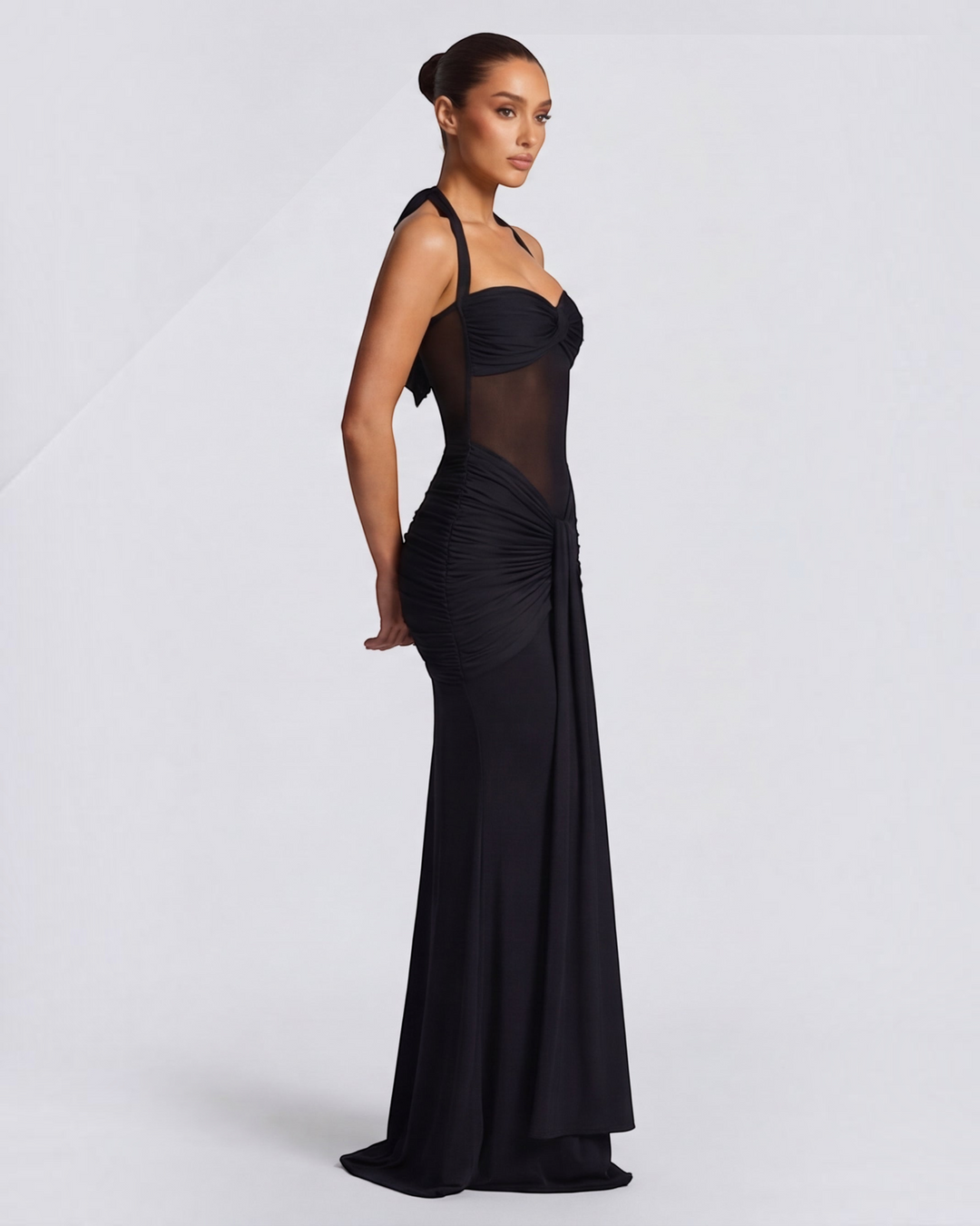 Luna Moda black mermaid gown with mesh waist detail and ruched hips worn by a model in a side profile view