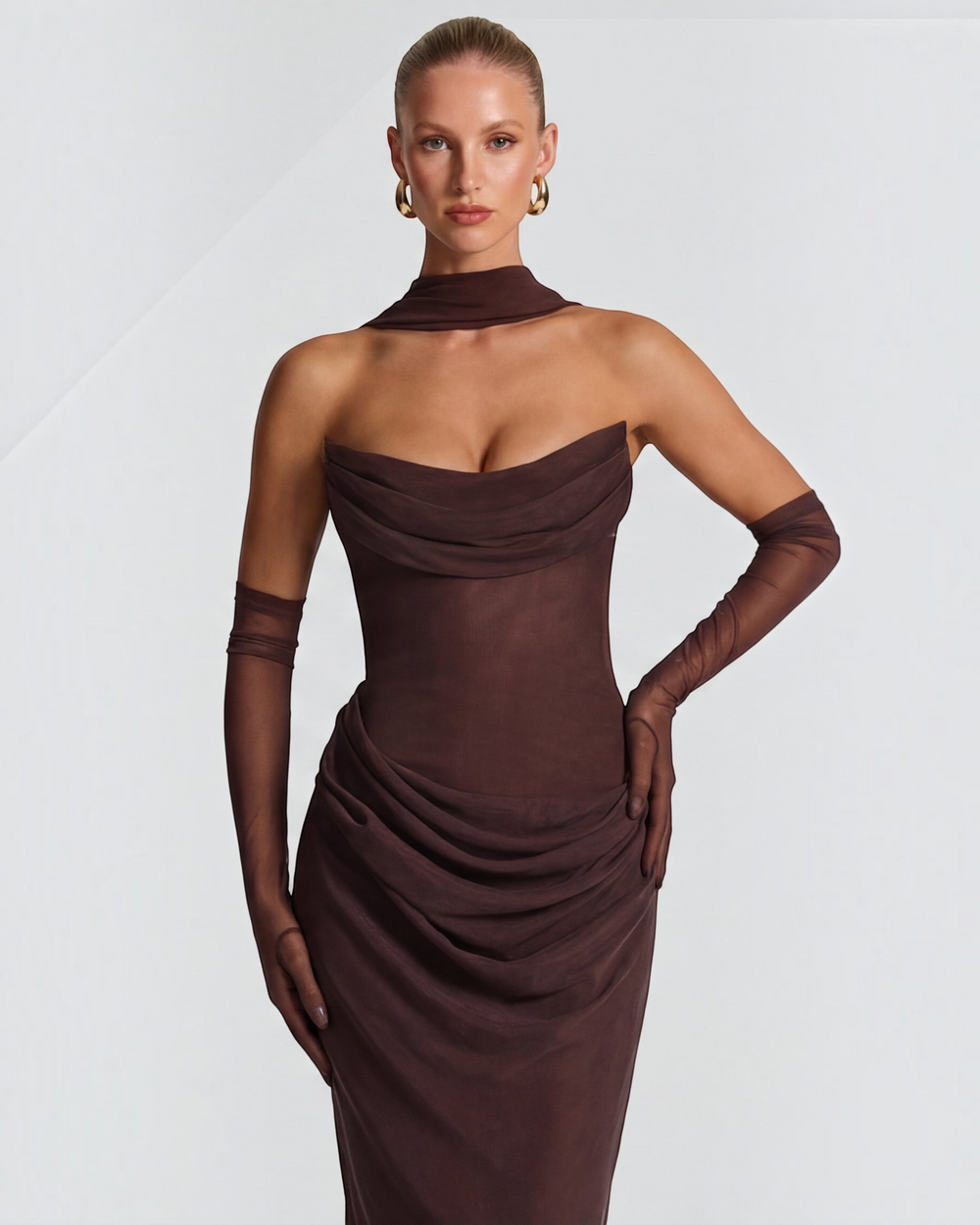 Luna Moda brown sculpting maxi dress with draped bodice and sheer mesh fabric on a model with elegant accessories.