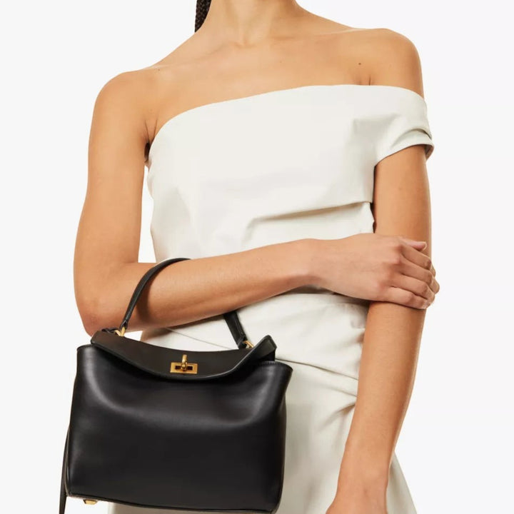 Luna Moda FEDERICA structured black vegan leather handbag with gold turn-lock closure held by a model