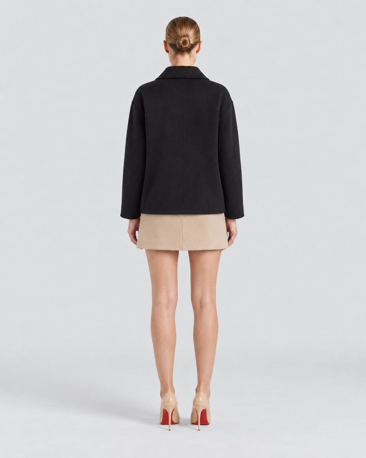 Luna Moda Amanda black oversized coat worn by a model from the back view with a beige skirt and heels
