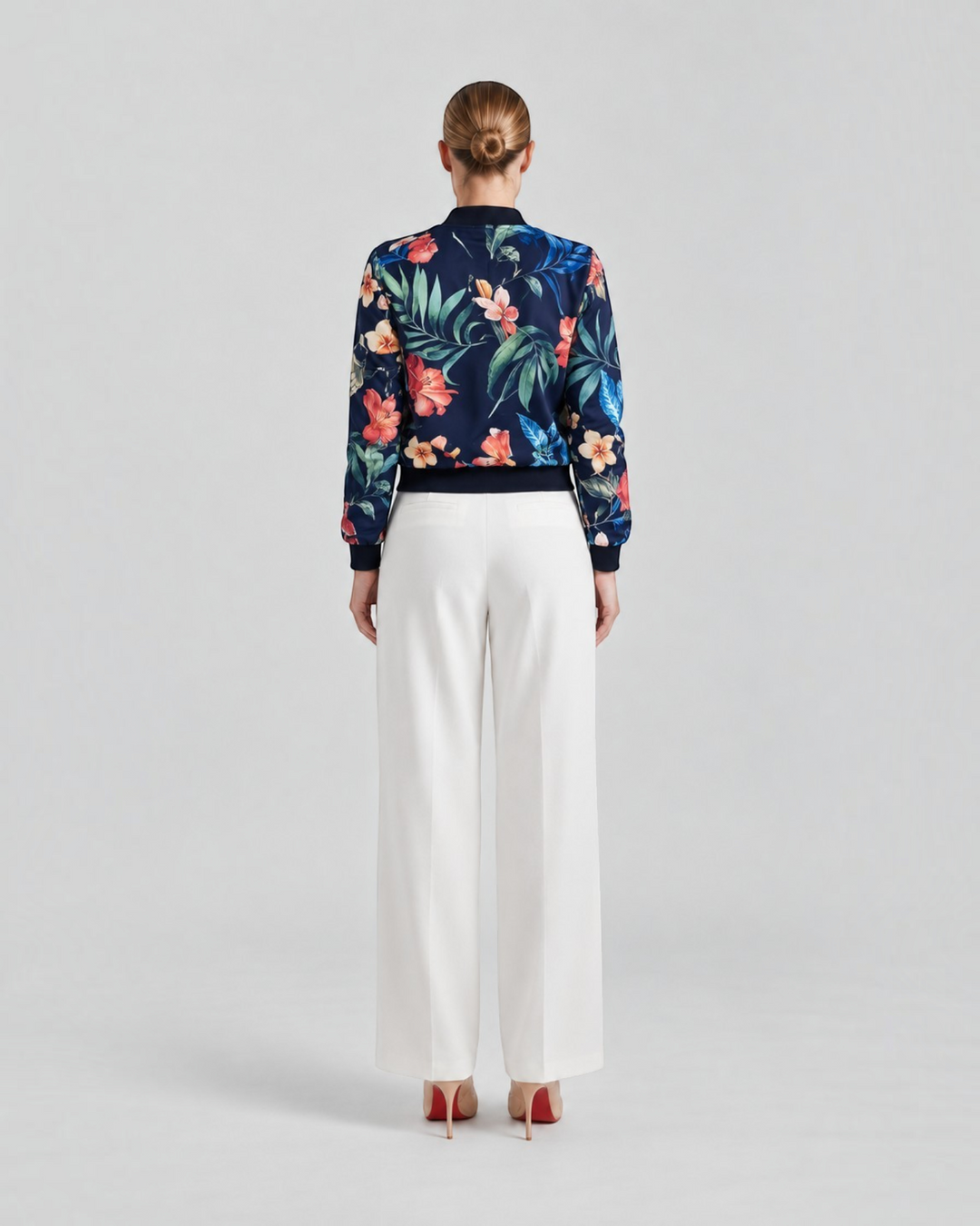 Luna Moda Arianna bomber jacket with vibrant floral print on navy blue polyester, worn with white trousers, back view