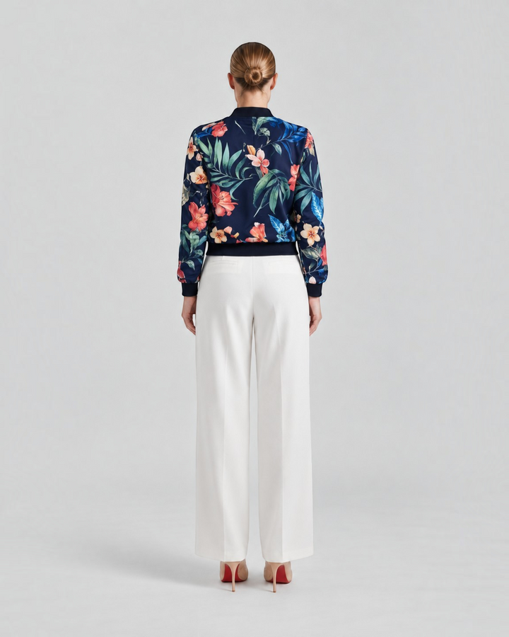 Luna Moda Arianna bomber jacket with vibrant floral print on navy blue polyester, worn with white trousers, back view