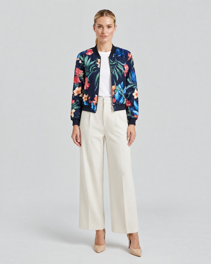 Luna Moda Arianna bomber jacket featuring a vibrant floral print on navy blue polyester, worn with cream trousers.