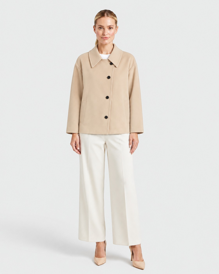 Luna Moda beige oversized coat with asymmetric button closure, classic collar, and front pockets on a female model