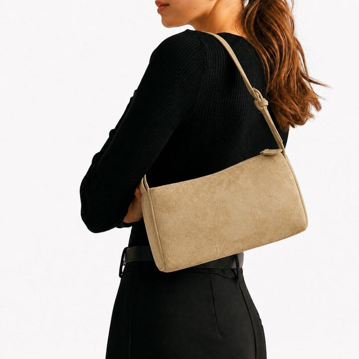 Luna Moda Marisa beige suede shoulder bag worn by a woman in a black outfit against a white background