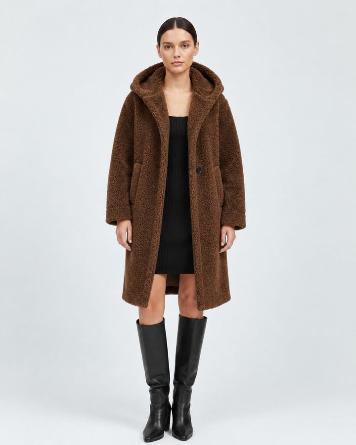 Luna Moda brown wool teddy coat with hood and patch pockets worn by a model over a black dress and knee-high boots